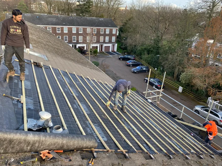 Roofers fixing new battens across a stripped terrace roof, Imperial Roofcraft roofing job in London