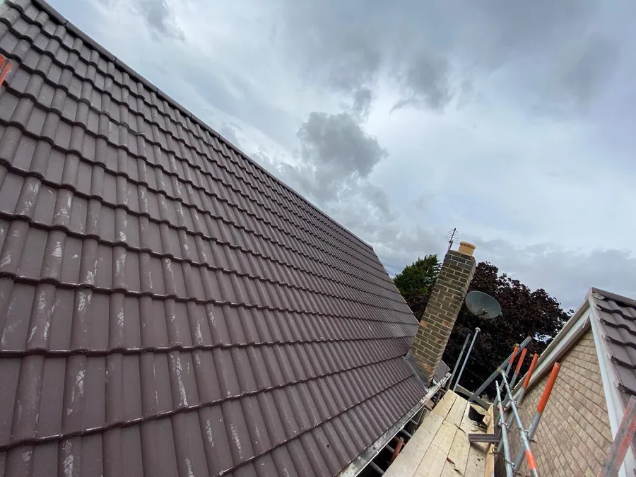 Dark brown tiled roof running up to a chimney stack, Imperial Roofcraft roofing job in London and Surrey
