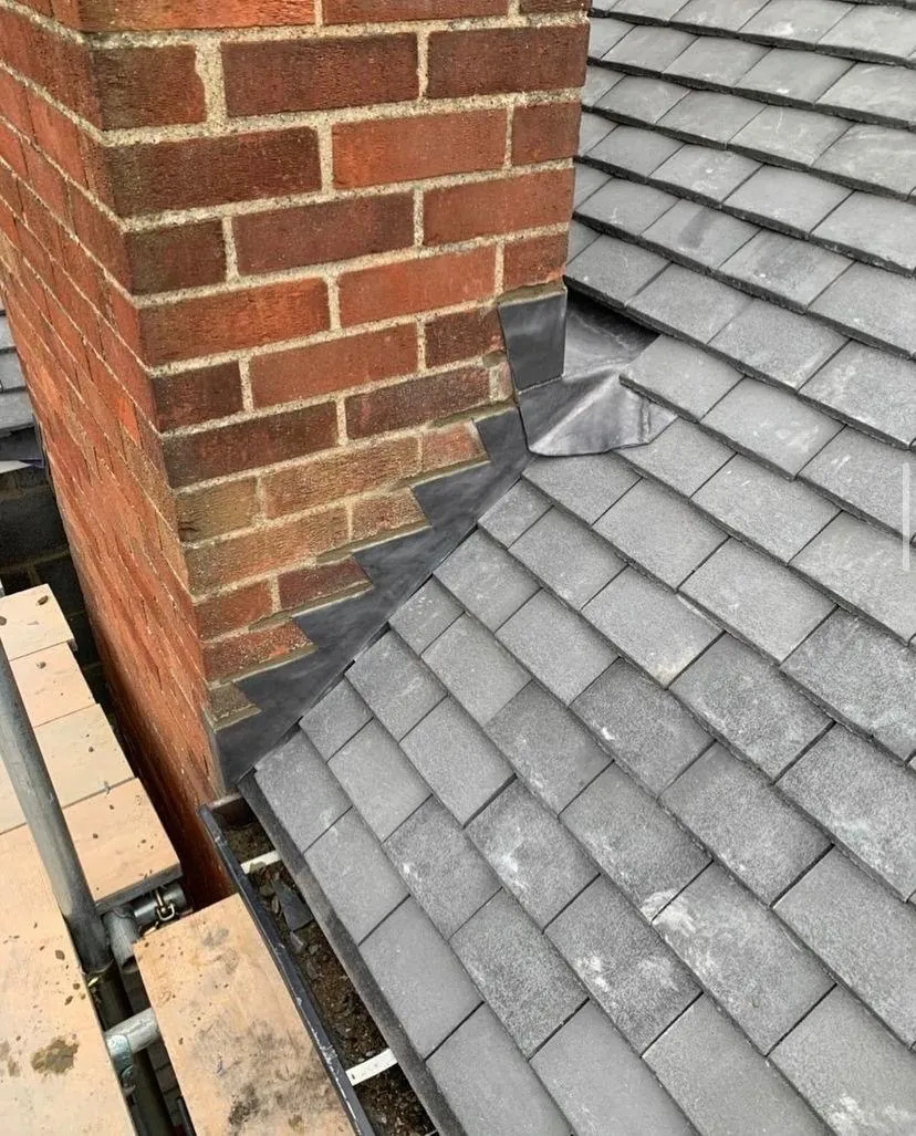 Lead soakers and flashing where grey tiles meet a brick chimney, Imperial Roofcraft roofing job in London