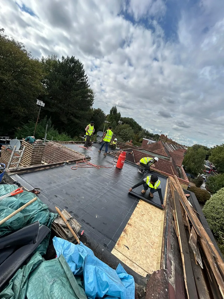 Roofers laying a new flat roof membrane over a fresh deck, Imperial Roofcraft roofing job in London