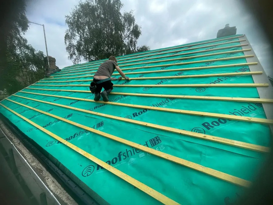 Roofer fixing battens over green breathable membrane, Imperial Roofcraft roofing job in London and Surrey