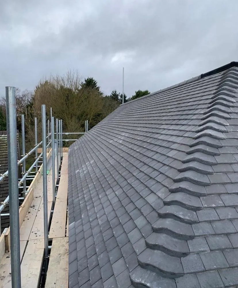 Grey tiled roof with scaffold at the eaves, Imperial Roofcraft roofing job in London