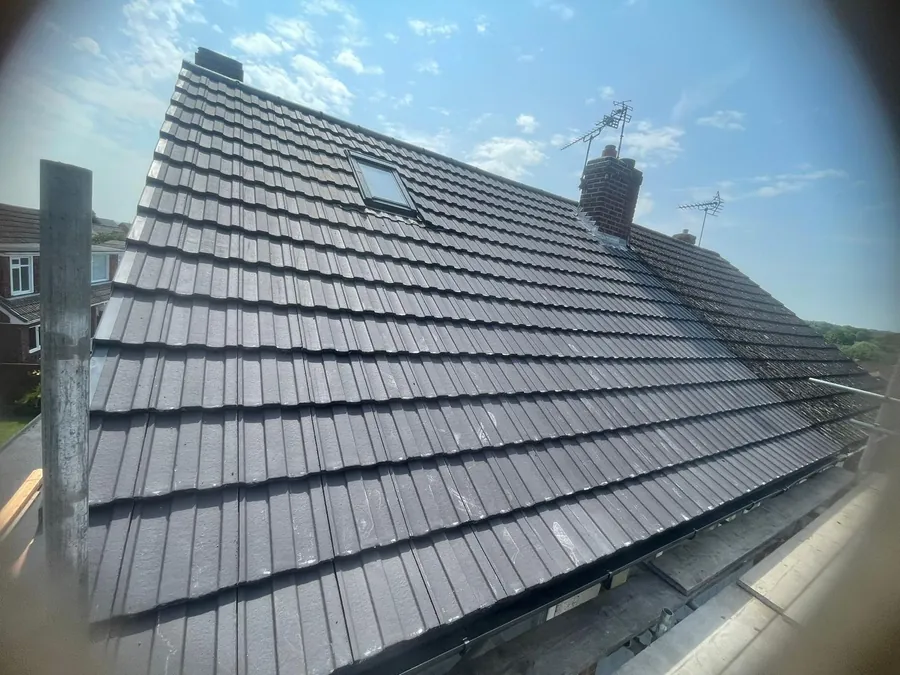 Finished grey tiled roof with a rooflight and chimney, Imperial Roofcraft roofing job in London and Surrey