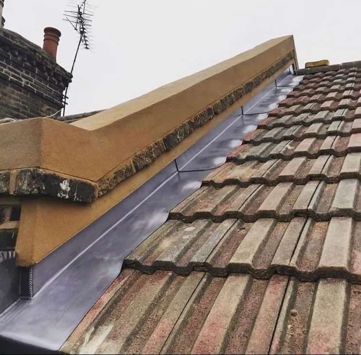 Lead flashing along a parapet coping above concrete tiles, Imperial Roofcraft roofing job in London