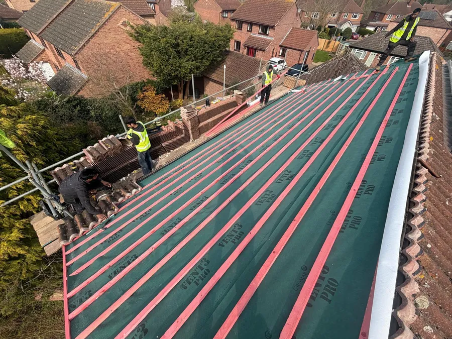Team battening over breathable membrane on a long roof slope, Imperial Roofcraft roofing job in London and Surrey