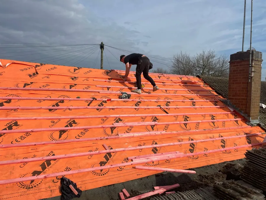 Roofer battening over orange breathable membrane, Imperial Roofcraft roofing job in London and Surrey
