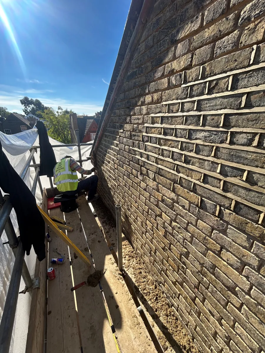 Roofer repointing a tall stock brick wall from the scaffold, Imperial Roofcraft roofing job in London and Surrey