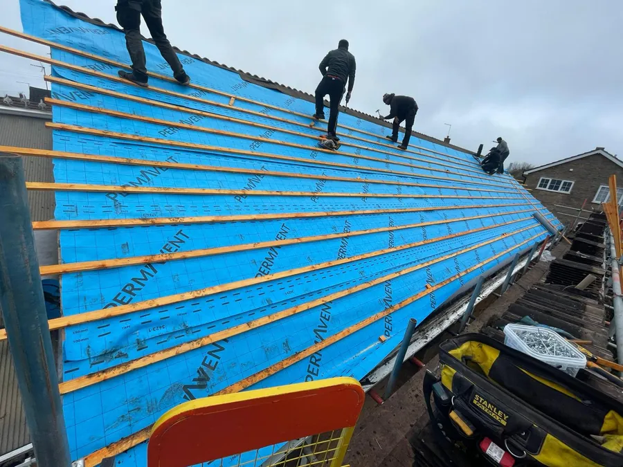 Three roofers battening over blue membrane, Imperial Roofcraft roofing job in London and Surrey