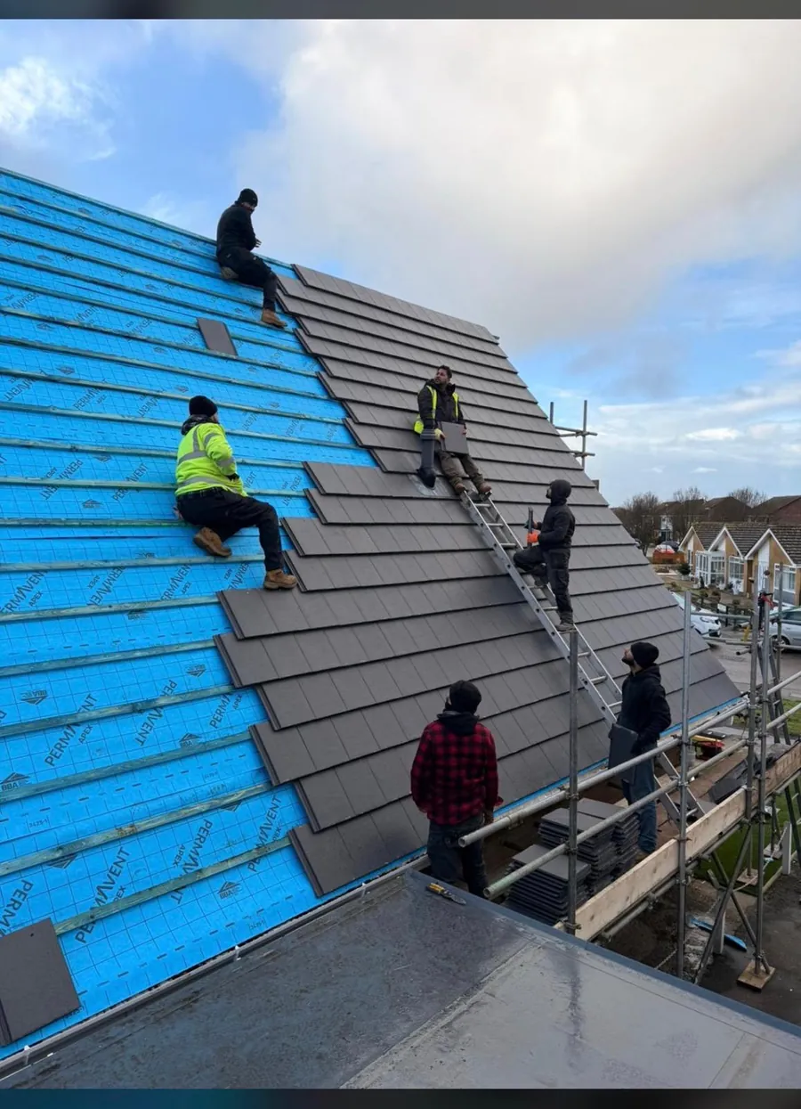 Four roofers tiling a slope over blue breathable membrane, Imperial Roofcraft roofing job in London and Surrey