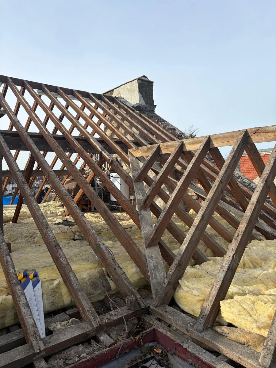 Exposed roof trusses beside a chimney during a full re-roof, Imperial Roofcraft roofing job in London and Surrey